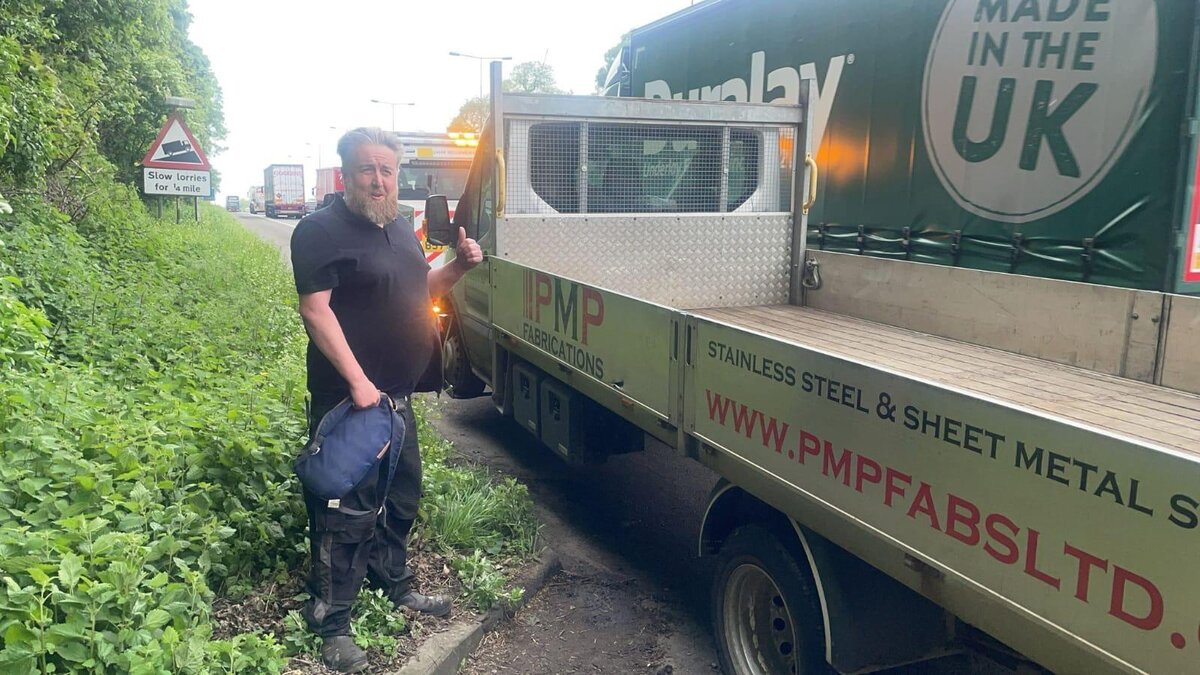 A Breakdown Man technician at the roadside with a PMP Fabrications stainless steel recovery truck on a slow-lorry lay-by.