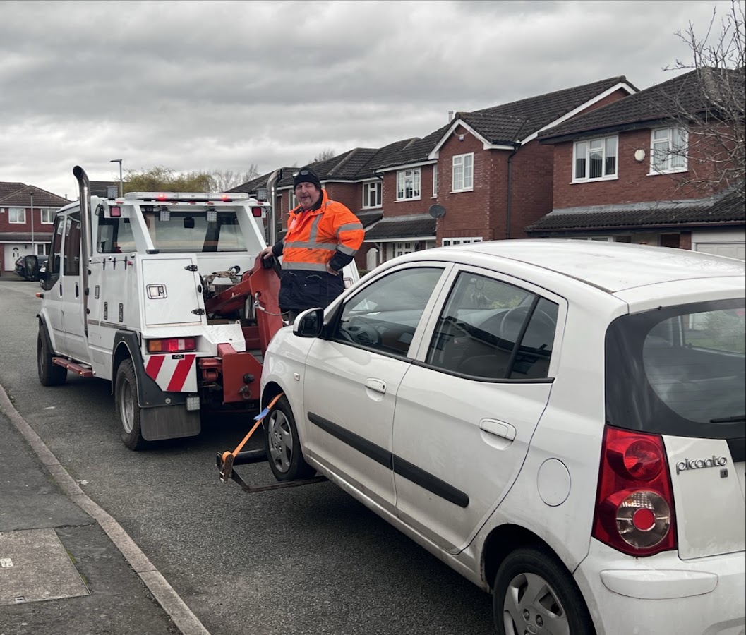A Breakdown Man technician smiling while towing a Kia Picanto — real job, real smile.