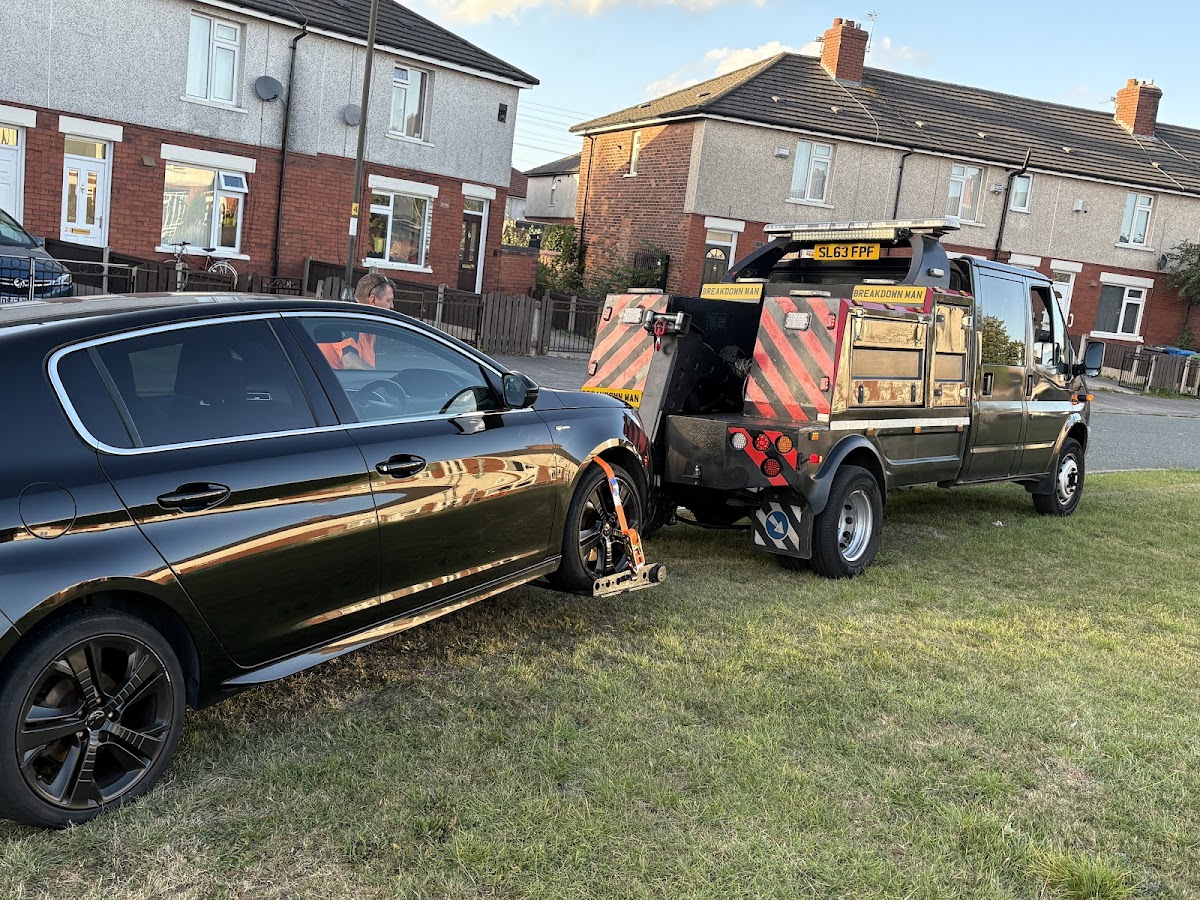 Towing a black BMW from a residential estate.