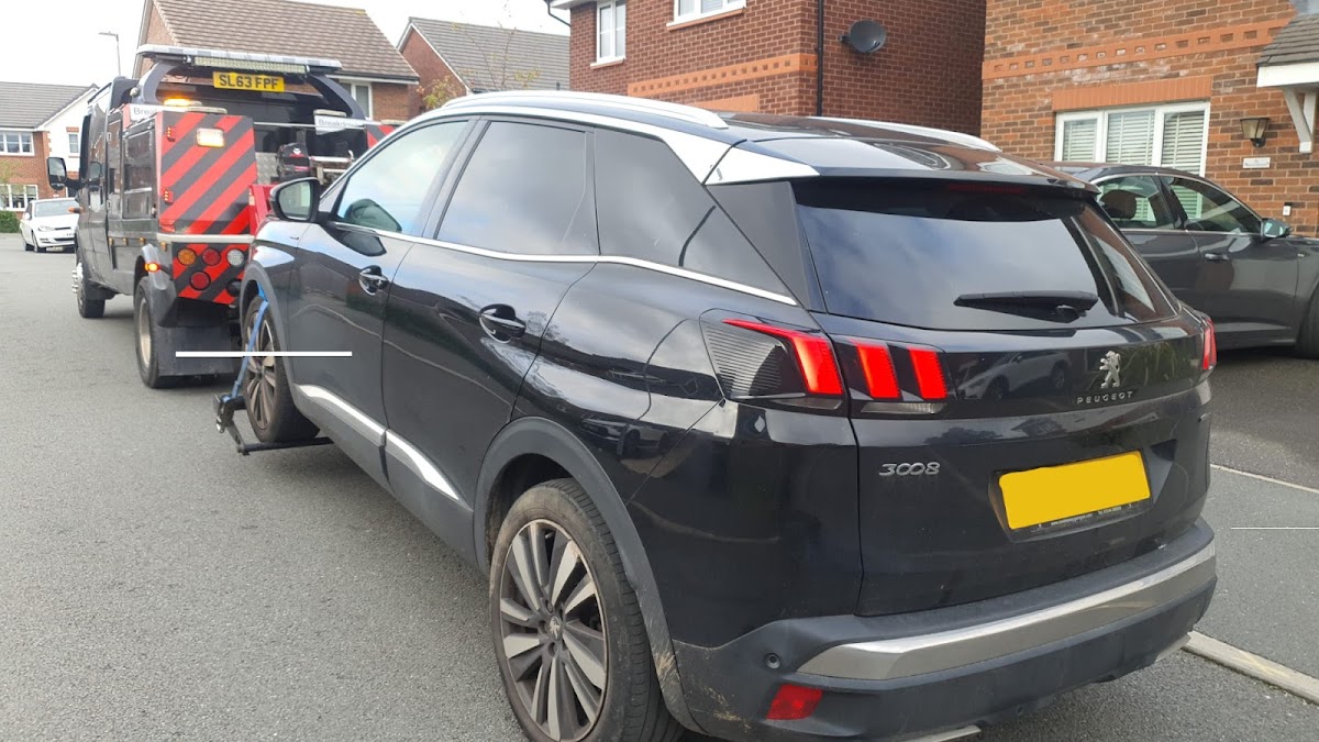 Towing a black Peugeot 3008 in a residential area.
